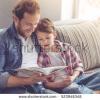 Stock photo father and son are reading a book and smiling while spending time together at home 523948348